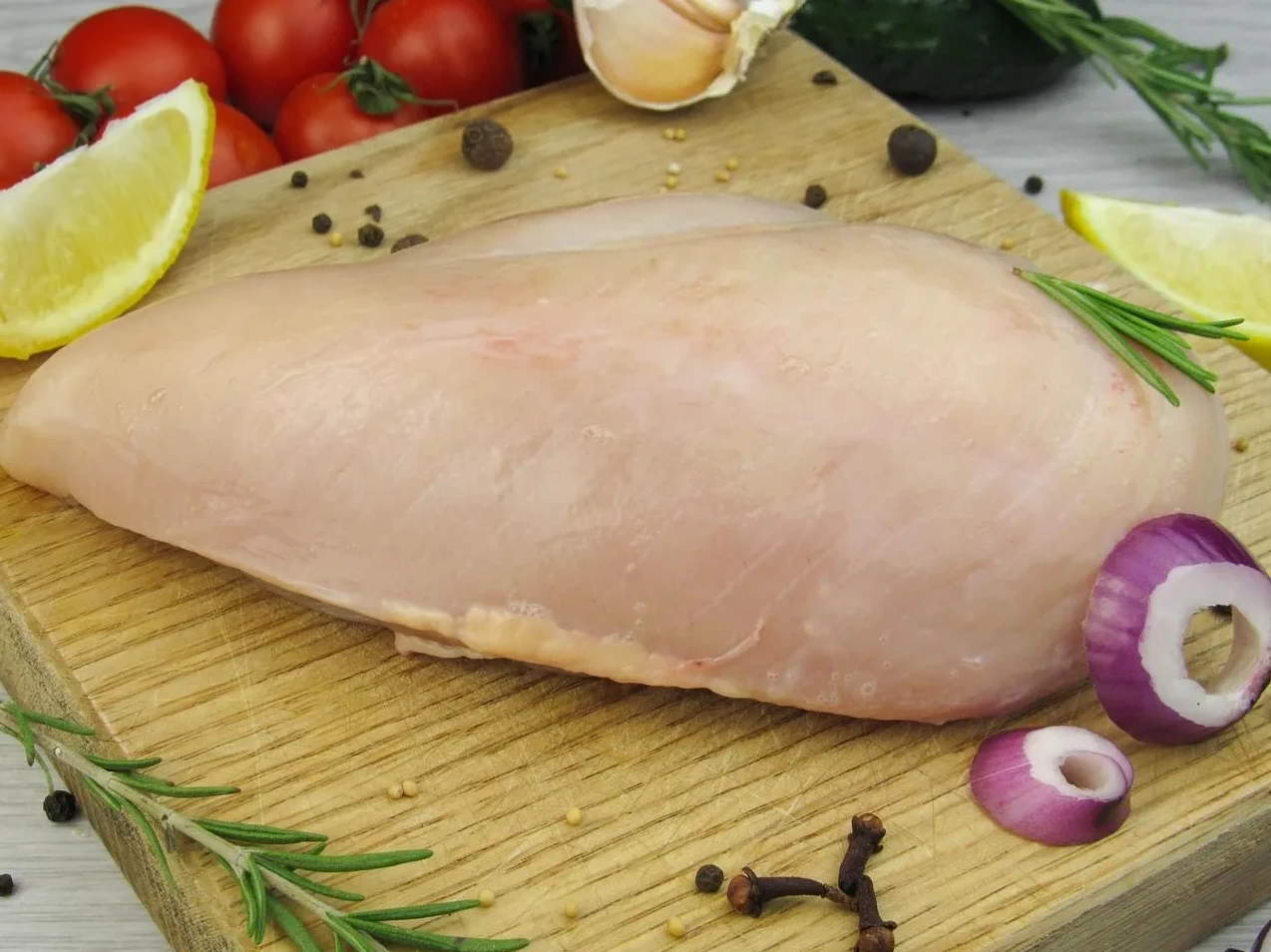 Sirova pileća prsa sa svježim začinima i povrćem na drvenoj podlozi