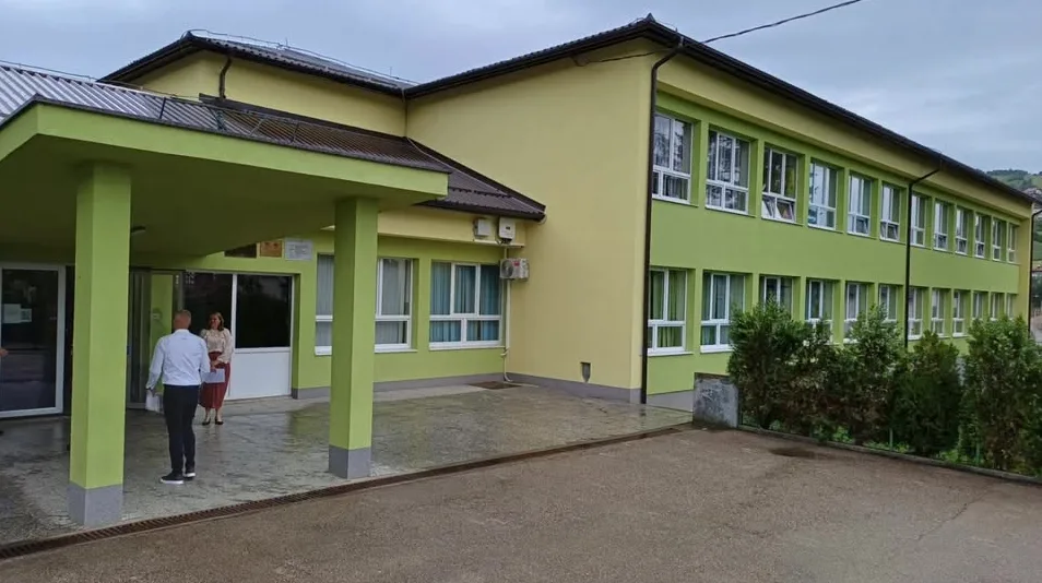 Moderna zelena školska zgrada sa dva sprata i velikim prozorima.