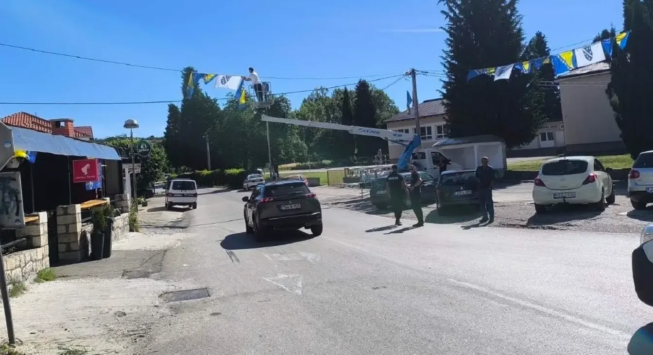 Radnici na dizalici postavljaju zastave Bosne i Hercegovine nad ulicom.