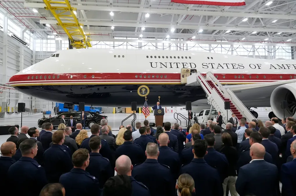 Predsjednik SAD-a govori pred mnoštvom ljudi pored aviona Air Force One u hangaru.