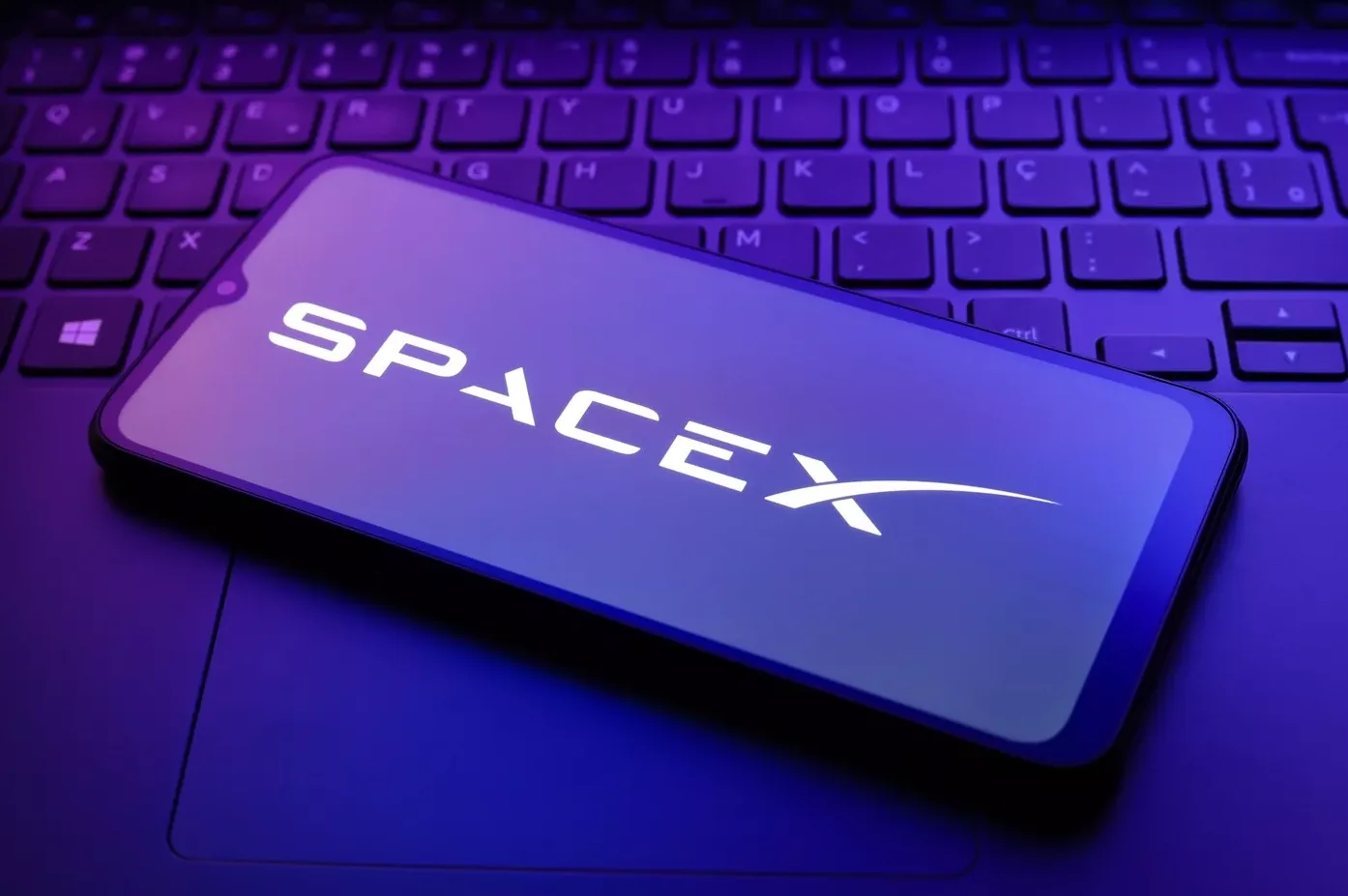 Logotip kompanije SpaceX na ekranu pametnog telefona postavljenog na tastaturi laptopa.