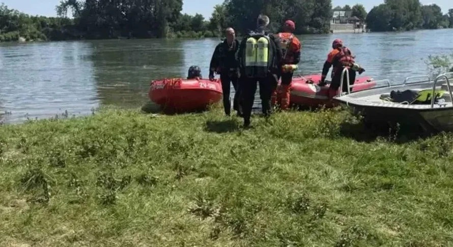 Spasioci u punoj opremi za ronjenje stoje na obali rijeke pored čamaca, pripremajući se za akciju.