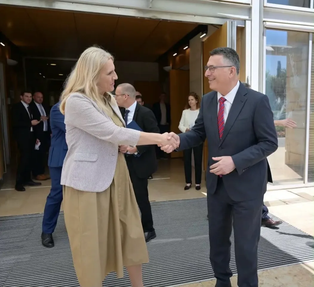 Političar i političarka se rukuju ispred zgrade