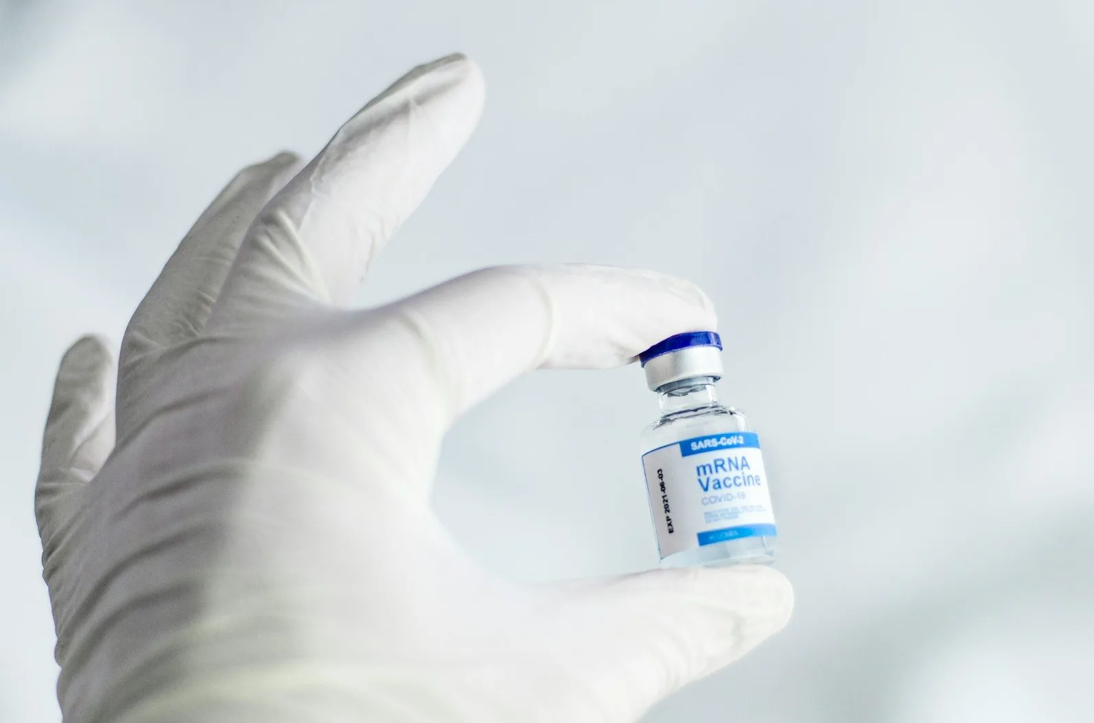 Vakcina protiv COVID-19 napravljena tehnologijom mRNK, koju drži ruka u bijeloj medicinskoj rukavici.