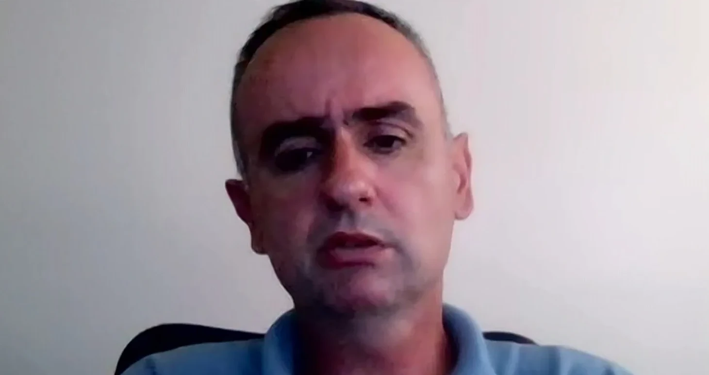 Muškarac srednjih godina gleda u kameru na video pozivu.