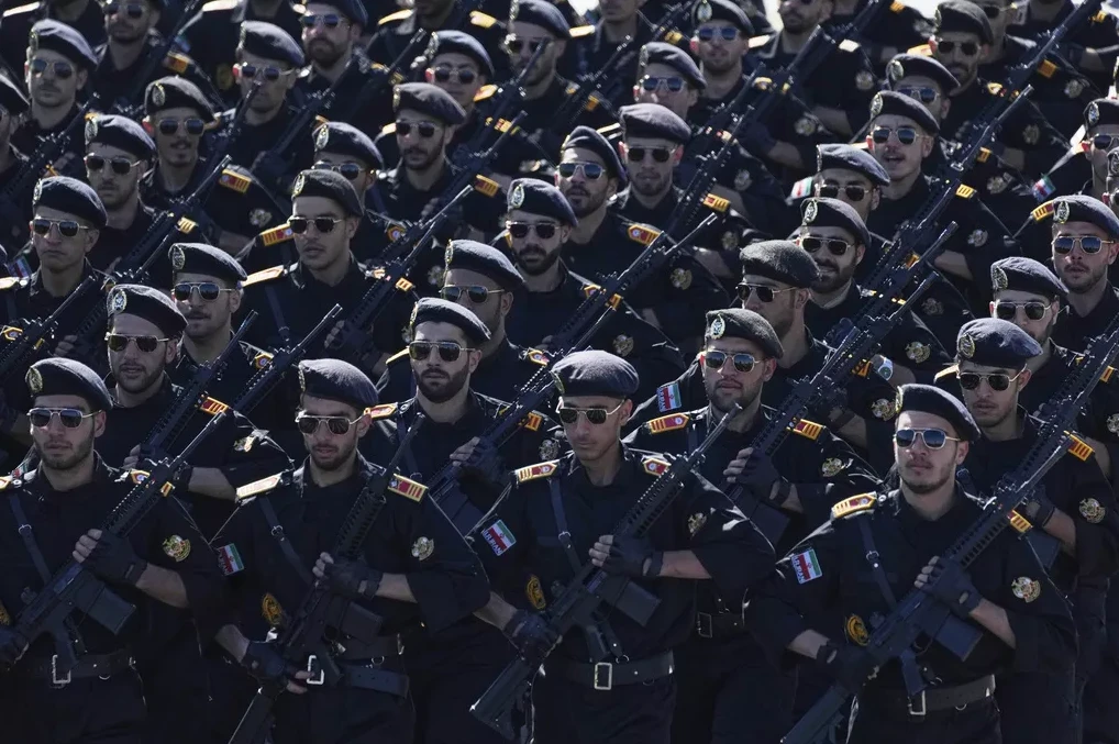 Pripadnici iranske vojske u crnim uniformama i beretkama, noseći automatske puške, marširaju.
