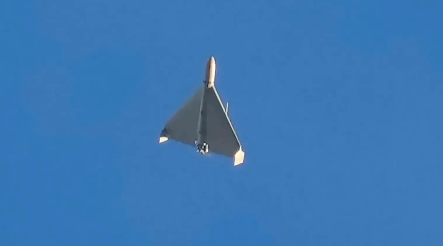 Vojni dron sa trokutastim krilima kako leti na čistom plavom nebu