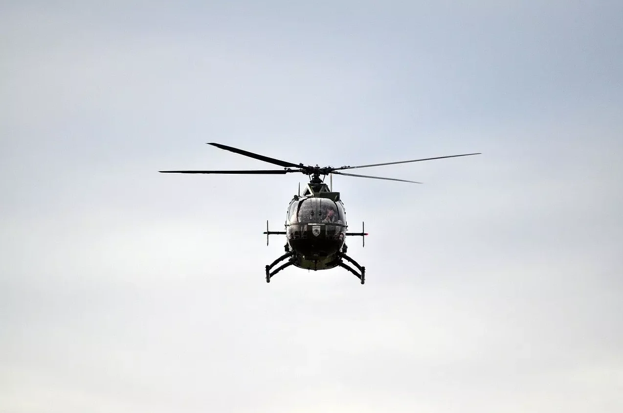 Vojni helikopter u letu sa pilotskom kabinom i rotorom u fokusu.