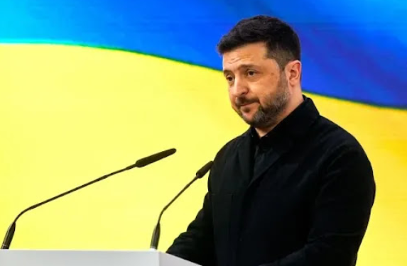 Volodimir Zelenski stoji za govornicom ispred ukrajinske zastave