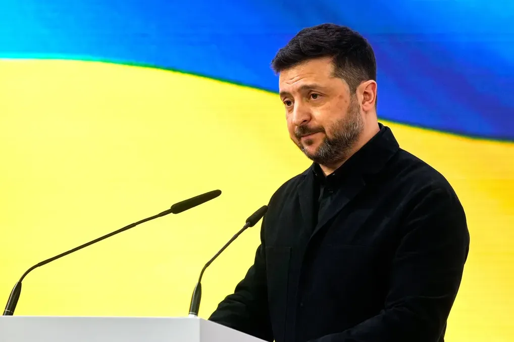 Predsjednik Ukrajine Volodimir Zelenski obraća se sa podijuma, sa ukrajinskom zastavom u pozadini.