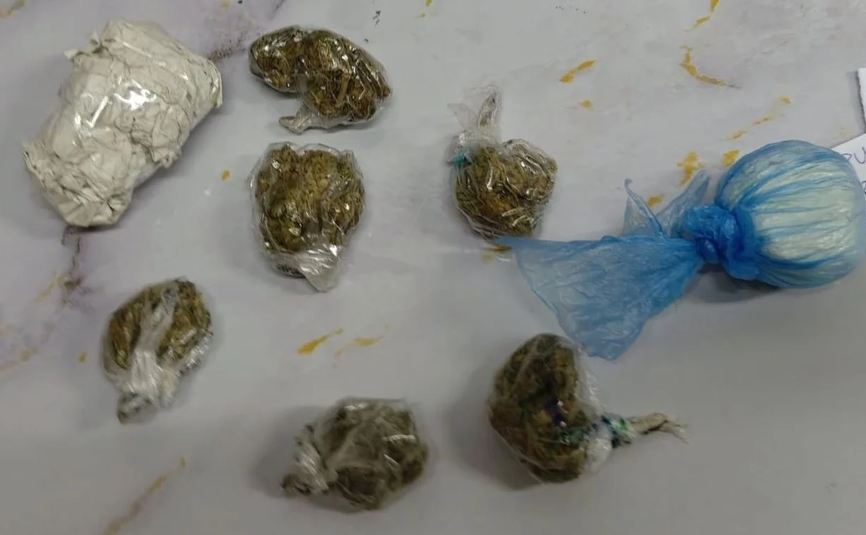 Prikaz više paketa sa zaplijenjenom marihuanom i jednom većom vrećicom bijelog praha, sve umotano u plastične kese.