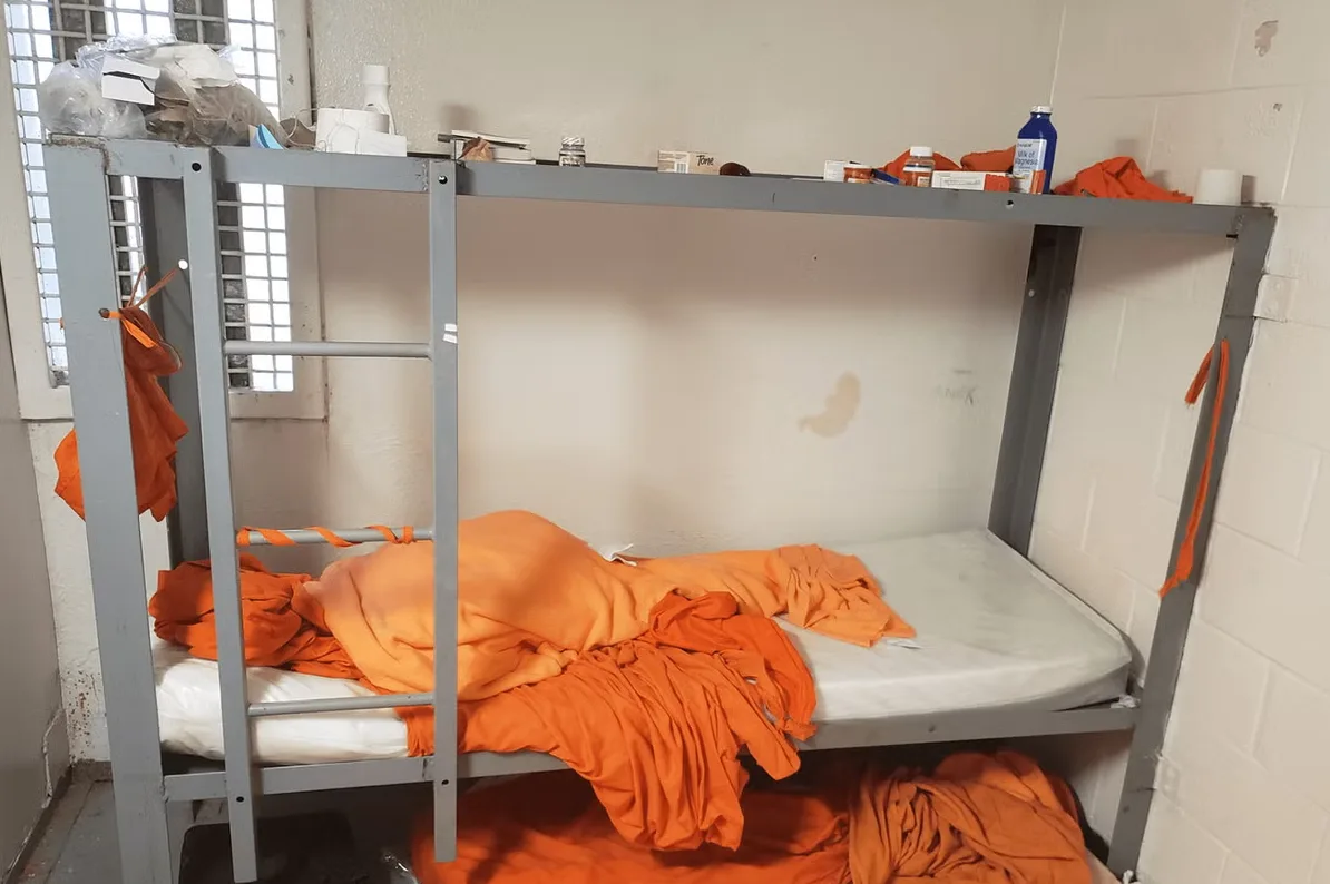 Krevet na sprat sa narandžastom posteljinom i nekoliko predmeta na gornjoj polici
