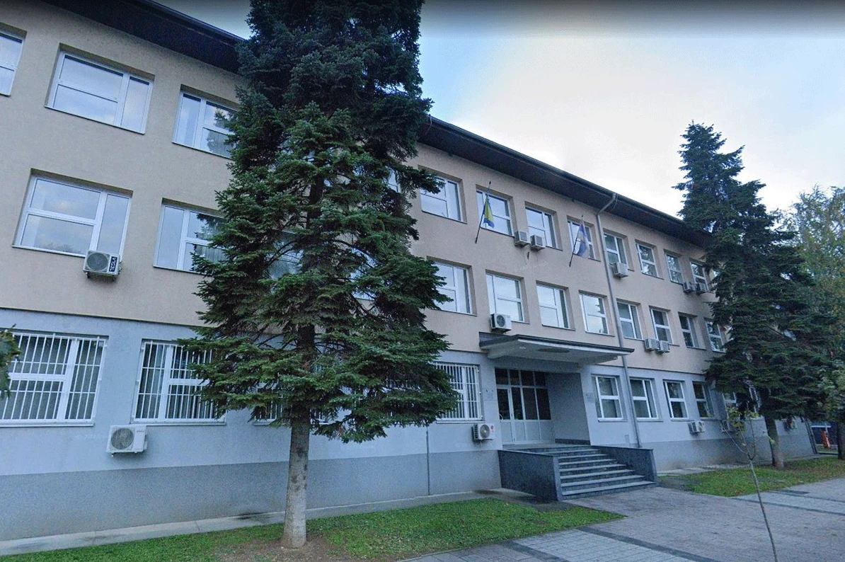 Fasada zgrade sa nekoliko spratova, sa velikim prozorima, klima uređajima i drvećem ispred.