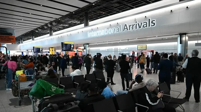 Putnici sa prtljagom u aerodromskom terminalu, sa natpisom 'International Arrivals'.