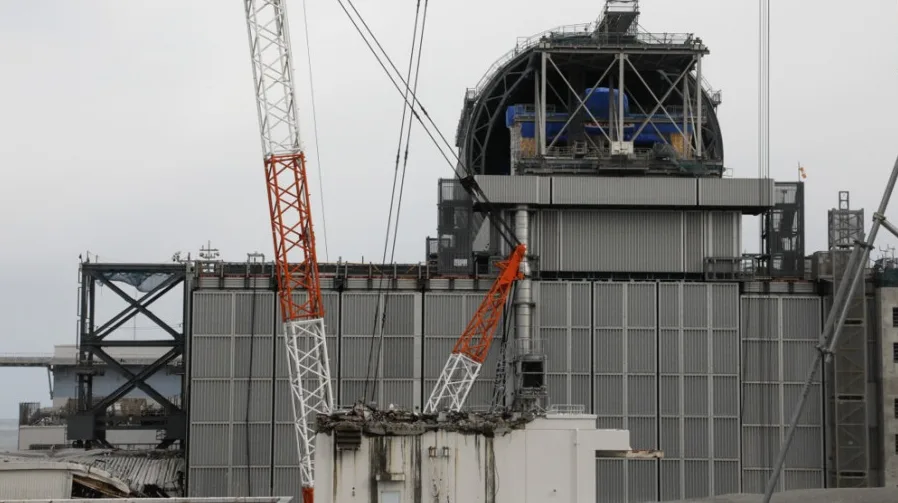 Fotografija prikazuje masivnu građevinsku konstrukciju sa nekoliko dizalica u upotrebi, sugerirajući tekuće radove na velikom industrijskom ili infrastrukturnom projektu.