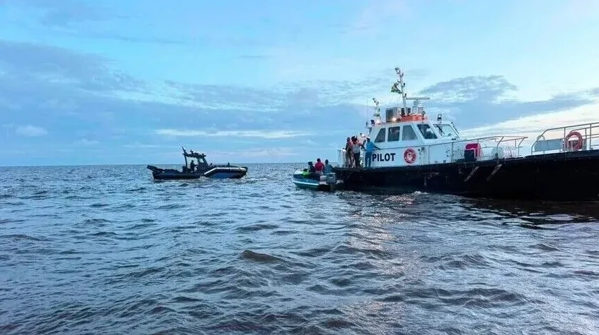 Brodica s oznakom 'PILOT' usidrena je na pučini, dok se prema njoj približavaju dvije manje brodice s ljudima.