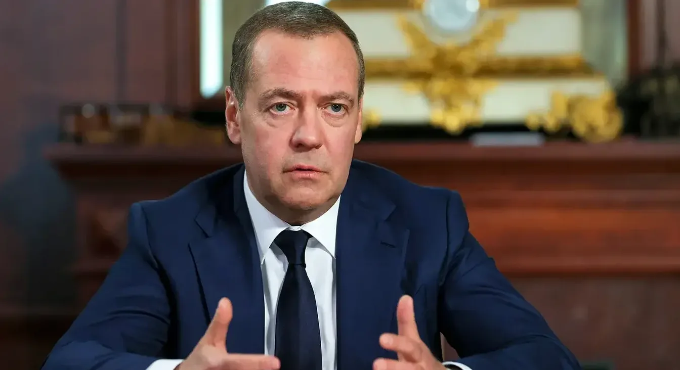 Portret Dmitrija Medvedeva u tamnoplavom odijelu i bijeloj košulji s tamnom kravatom, koji govori i gestikulira rukama.