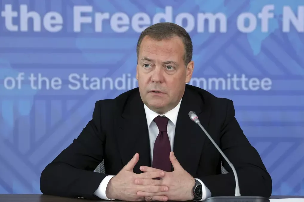 Dmitry Medvedev sjedi za stolom sa mikrofonom ispred sebe, sa rukama sklopljenim ispred sebe.