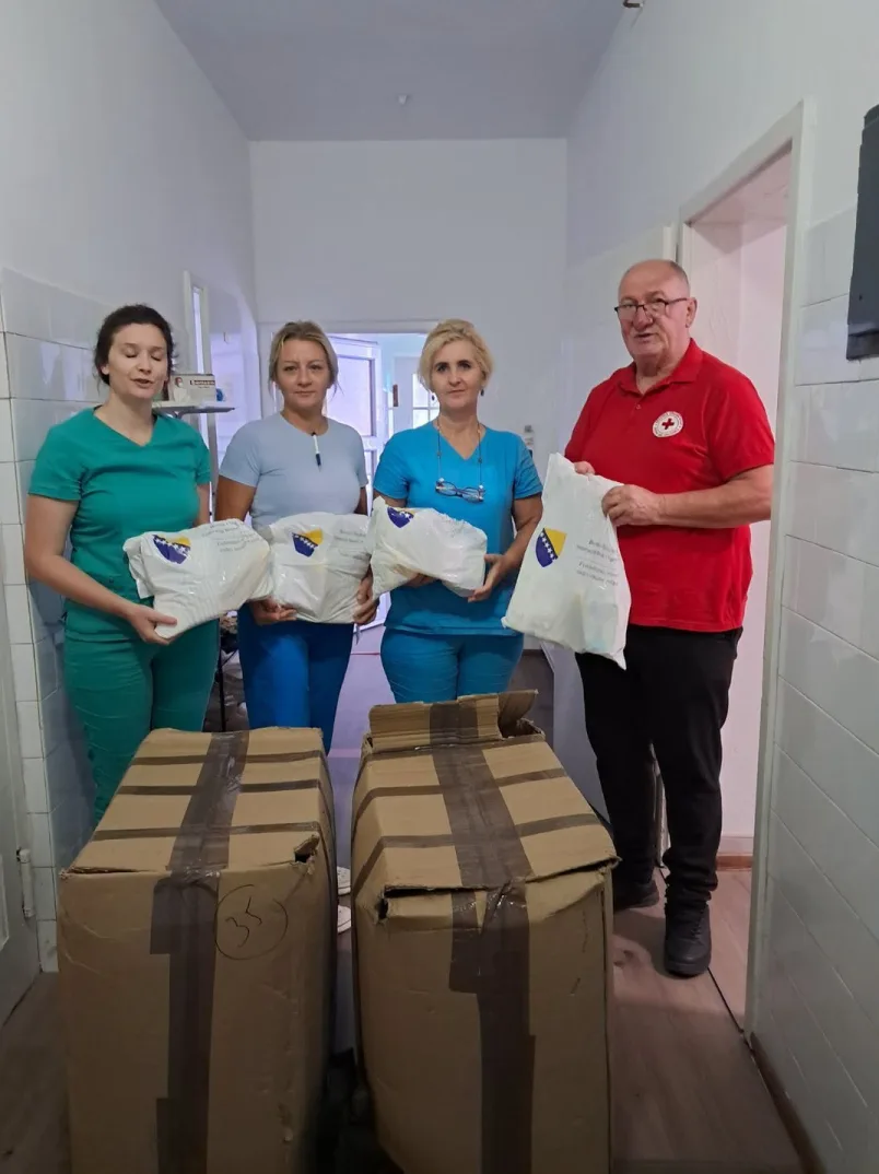Medicinski radnici i predstavnik Crvenog krsta drže pakete sa pomoći u hodniku zdravstvene ustanove.