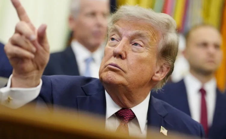 Donald Tramp, bivši predsjednik Sjedinjenih Država, podiže prst u znak ukazivanja, dok se ostali ljudi naziru u pozadini.