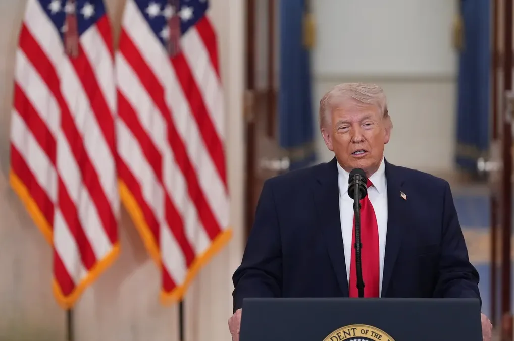 Donald Trump govori u mikrofon ispred dvije američke zastave