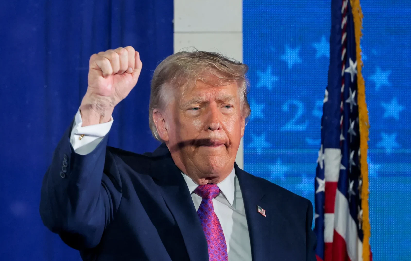 Donald Trump sa podignutom pesnicom i američkom zastavom