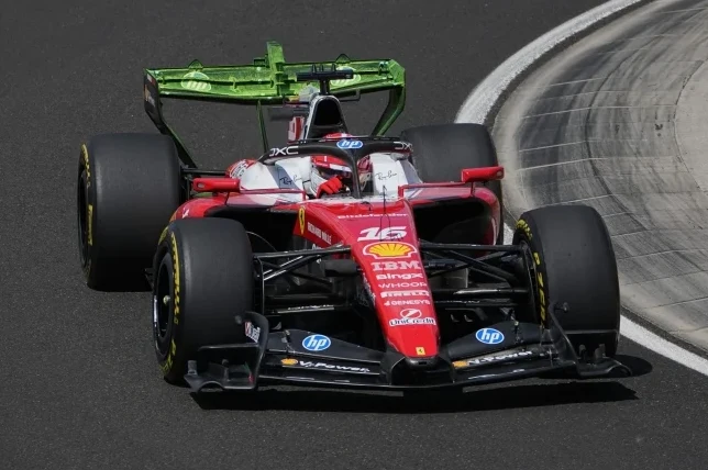 Crveni bolid Formule 1 s brojem 16 i zelenim stražnjim krilom kako vozi po stazi.