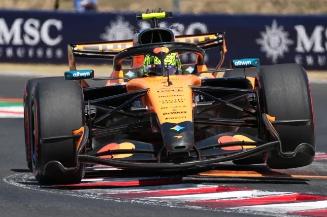 Narandžasti Formula 1 bolid sa crnim detaljima na stazi.