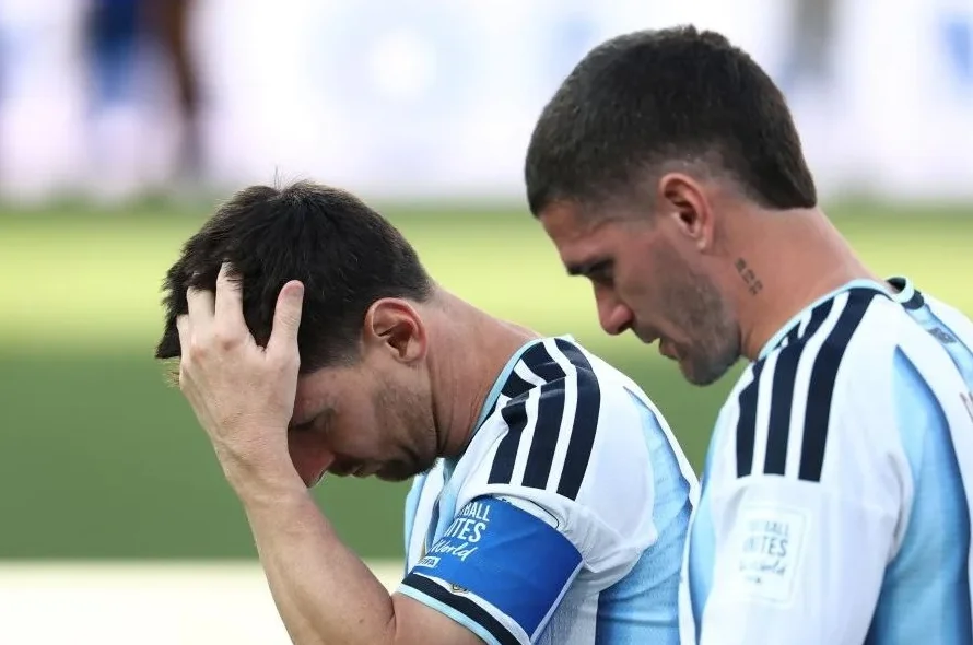 Lionel Messi drži se za glavu, vidno razočaran, uz rame mu stoji Rodrigo De Paul.