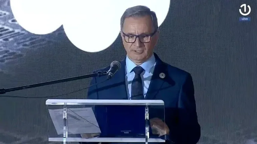 Državnik u tamnom odijelu i plavoj košulji s kravatom govori za govornicom ispred mikrofona, s bijelim oblačićem i logom N1 u pozadini.