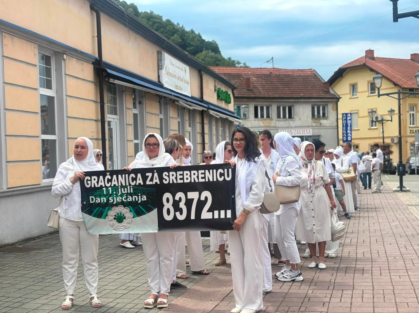 Žene u bijelim odijelima i maramama nose transparent "Gračanica za Srebrenicu 11. juli Dan sjećanja 8372...".