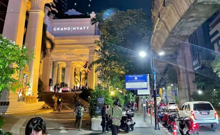 Ulaz u hotel Grand Hyatt u Bangkoku noću, saobraćaj i ljudi ispred.