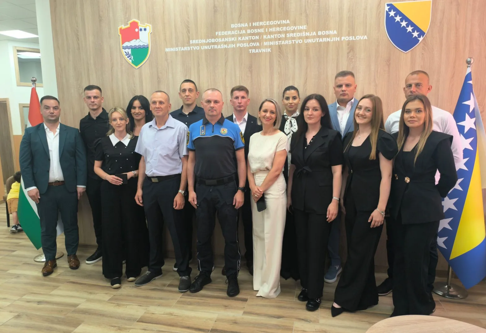 Grupa zvaničnika pozira za fotografiju u kancelariji, sa grbom Bosne i Hercegovine i Zastavom Federacije BiH u pozadini.