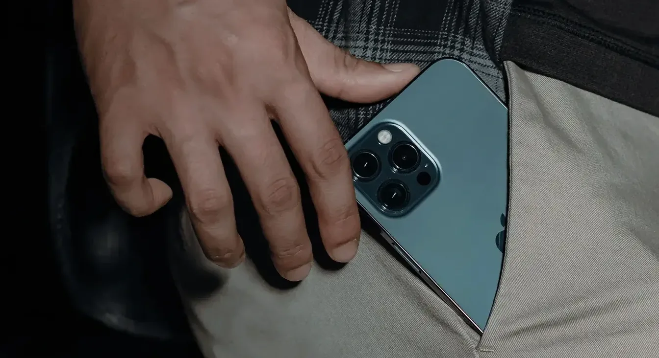 Ruka stavlja iPhone sa tri kamere u džep.