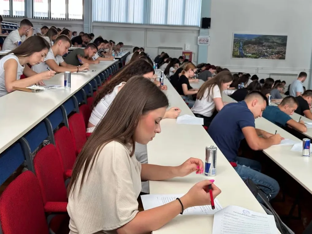 Grupa studenata polaže ispit sjedeći u amfiteatru.