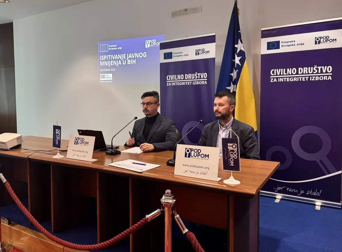 Dva muškarca sjede za stolom, predstavljajući prezentaciju o ispitivanju javnog mnijenja u Bosni i Hercegovini.