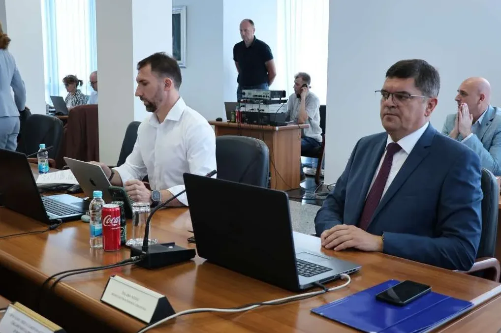 Ljudi na sastanku u konferencijskoj sali, fokus na dva muškarca u odijelima