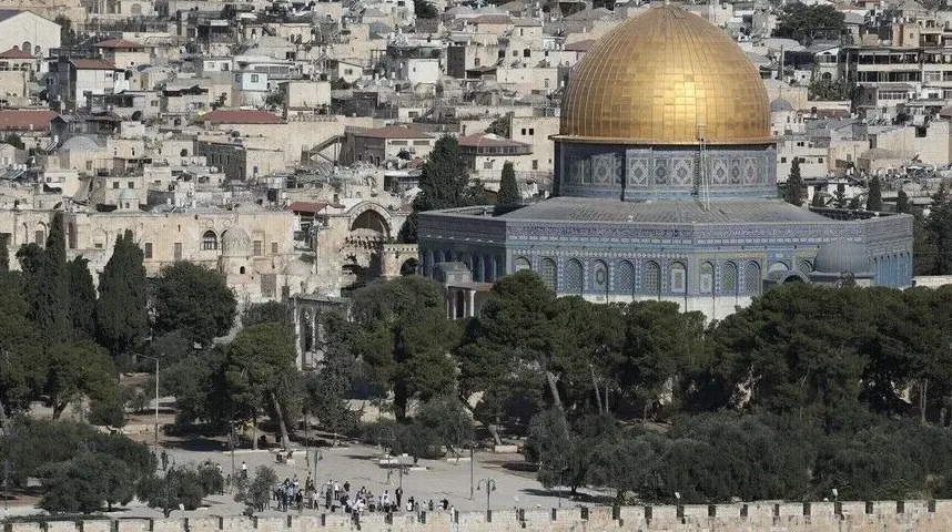 Zlatna kupola džamije Kupola na stijeni (Dome of the Rock) u Jerusalemu, okružena drvećem i starim gradskim zdanjima.