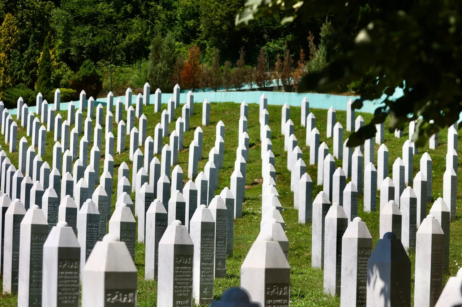 Redovi bijelih nišana na zelenoj travi Memorijalnog centra Srebrenica.