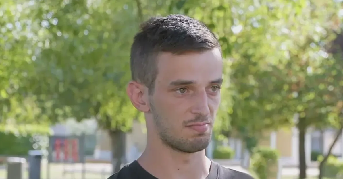 Portret mladog muškarca sa kratkom kosom i bradom kako gleda lijevo.