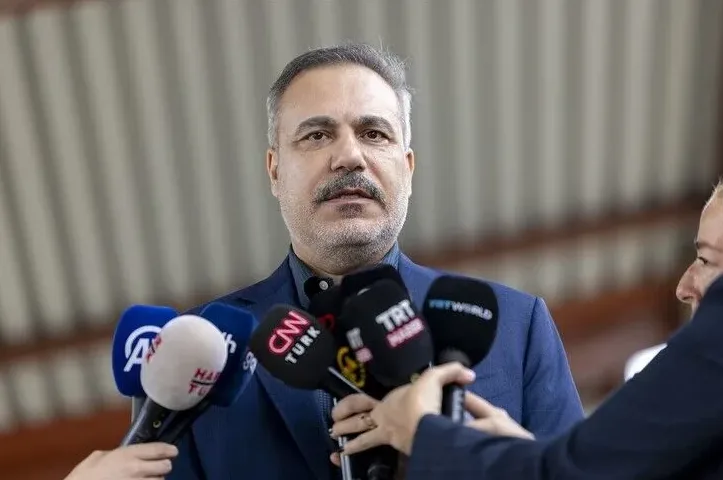 Muškarac sa brkovima u tamnom odijelu okružen sa više mikrofona raznih medijskih kuća poput CNN Turk, TRT World i AA.