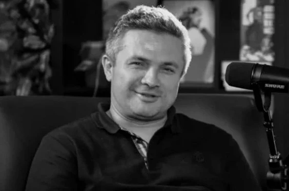 Crno-bijela fotografija muškarca kako sjedi u blizini mikrofona.