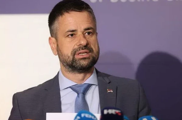 Muškarac u tamnom odijelu i plavoj kravati sa šarama govori pred novinarima.
