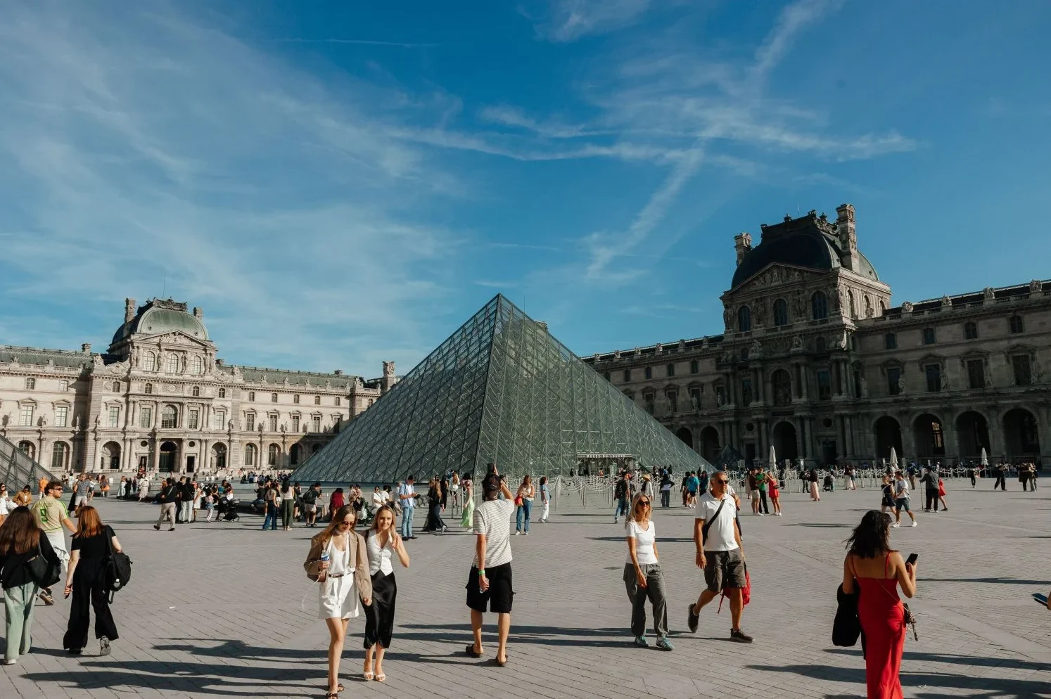 Turisti fotografišu poznatu staklenu piramidu ispred muzeja Lujvr u Parizu.
