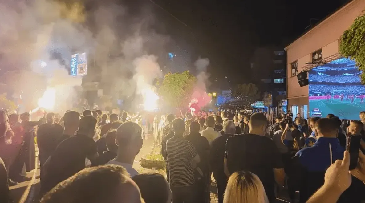 Grupa navijača slavi uz baklje i dim.