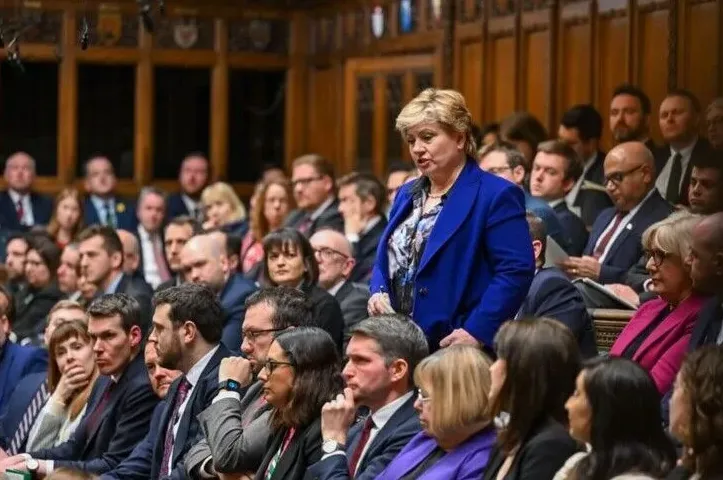 Žena u plavom sakou govori u parlamentu dok se drugi poslanici vide u pozadini.