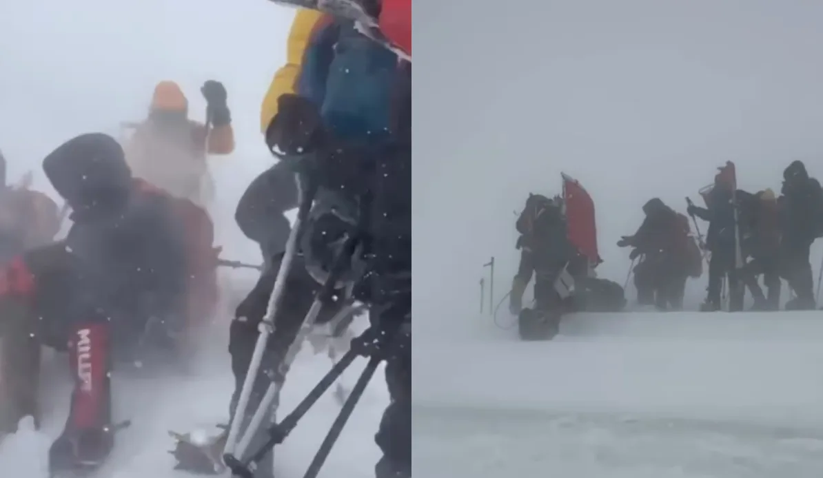 Grupa planinara sa crvenom zastavom na vrhu planine tokom olujnog nevremena.