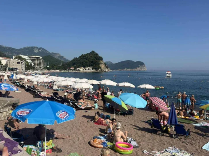 Grupa ljudi uživa na sunčanoj plaži okruženoj planinama.