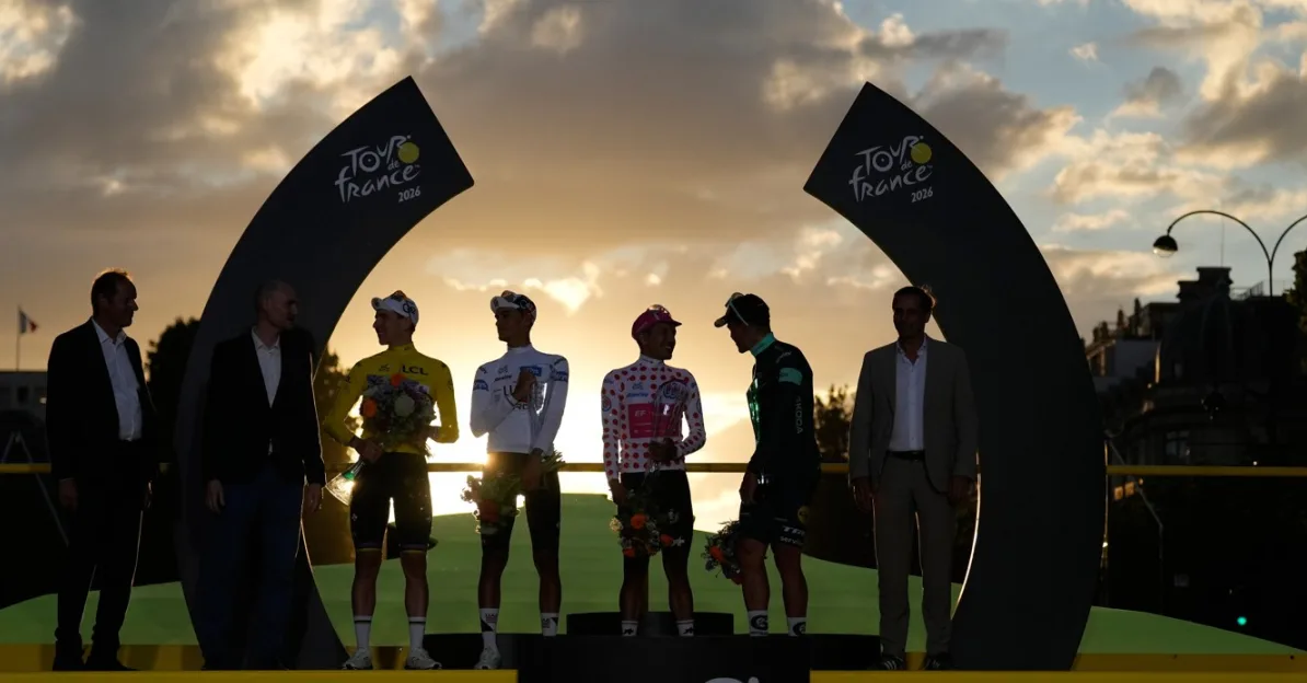 Pobjednici biciklističke utrke Tour de France stoje na postolju tokom ceremonije dodjele nagrada pri zalasku sunca.