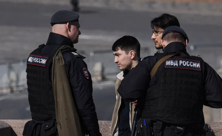 Dva ruska policajca u uniformi razgovaraju sa dvojicom muškaraca na ulici.